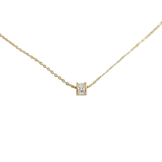 Gold necklace with a small diamond pendant on a light gray background