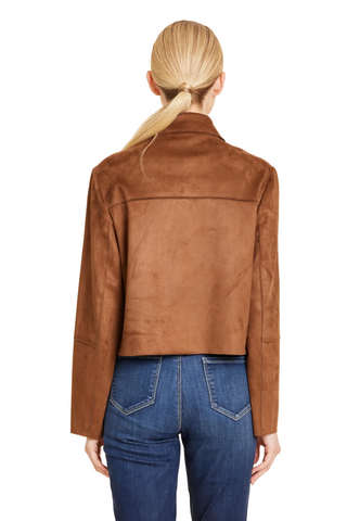 A woman viewed from the back wearing a cropped brown suede jacket and blue jeans against a plain beige studio background.