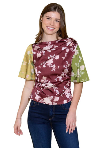 Woman wearing a maroon floral blouse with green sleeves against a light green background