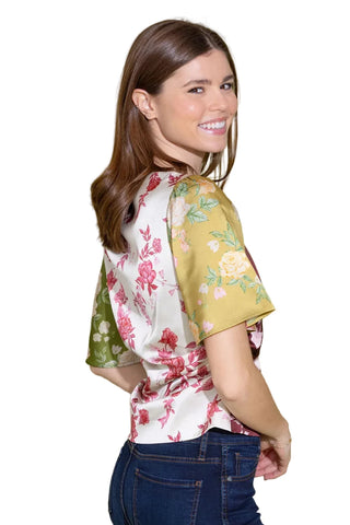 Woman wearing a floral blouse with green sleeves against a light green background
