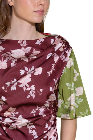 Close-up of a person wearing a floral-patterned garment with a green sleeve against a plain background