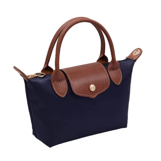 Navy handbag with brown leather handles and accents on a light gray surface.