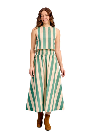 A woman modeling a sleeveless two-piece set with vertical green and cream stripes, consisting of a cropped top and a matching wide-leg skirt, paired with brown ankle boots against a solid light blue background.