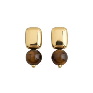 A pair of gold and brown drop earrings with a polished gold rectangular top and a round brown bead below, displayed on a light gray textured fabric background.