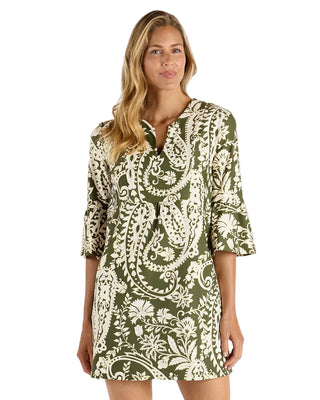 A woman modeling a short-sleeve mini dress with a green and cream paisley floral pattern, set against a plain white studio background.