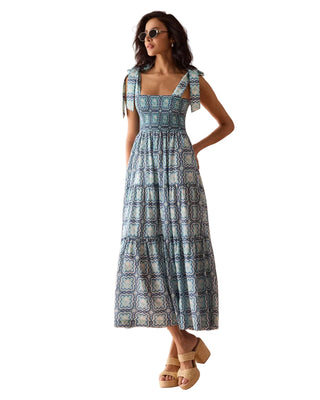 Woman wearing a blue patterned dress against a pink background