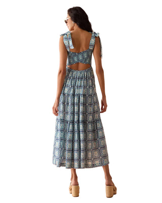 Woman wearing a blue patterned dress with cut-out back on a peach background
