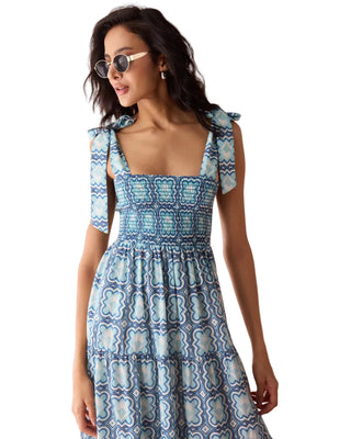 Woman wearing a blue patterned dress against a pink background