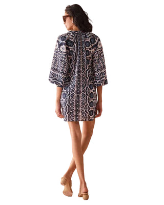 Woman wearing a patterned dress against a beige background