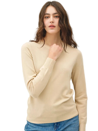 Woman wearing a beige sweater against a plain background